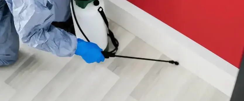 Chapman Pest Control technician applying cockroach treatment along a baseboard in a Cedar City, UT home